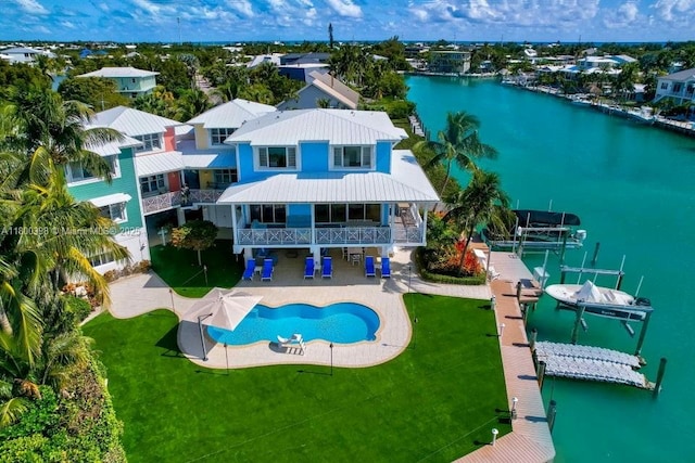 rear view of house with boat lift, an outdoor pool, a water view, a patio area, and a lawn