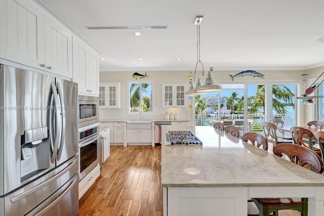 kitchen with stainless steel appliances, a center island, white cabinets, glass insert cabinets, and light wood-style flooring