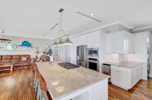 kitchen featuring appliances with stainless steel finishes, stacked washer / dryer, white cabinets, crown molding, and light wood-style flooring