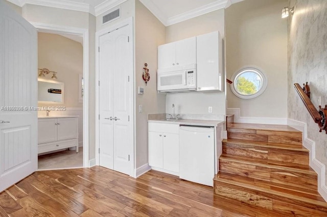 kitchen with white appliances, light wood finished floors, ornamental molding, light countertops, and white cabinets