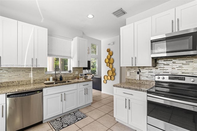 5832 NW 120th Ave, Coral Springs, FL 33076 - kitchen featuring appliances with stainless steel finishes, a sink, backsplash, white cabinetry, and light tile patterned flooring