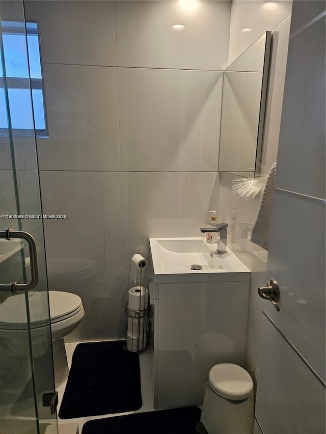 619 NE 14th Ave Unit 106, Hallandale Beach, FL 33009 - full bathroom featuring toilet, vanity, a shower stall, and tile walls