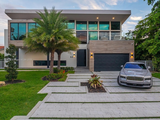 521 Holiday Dr, Hallandale Beach, FL 33009 - contemporary home with decorative driveway, an attached garage, a front yard, and stucco siding