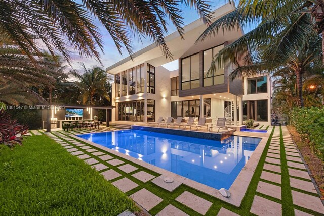521 Holiday Dr, Hallandale Beach, FL 33009 - pool at dusk with an in-ground hot tub, an outdoor pool, and a patio area