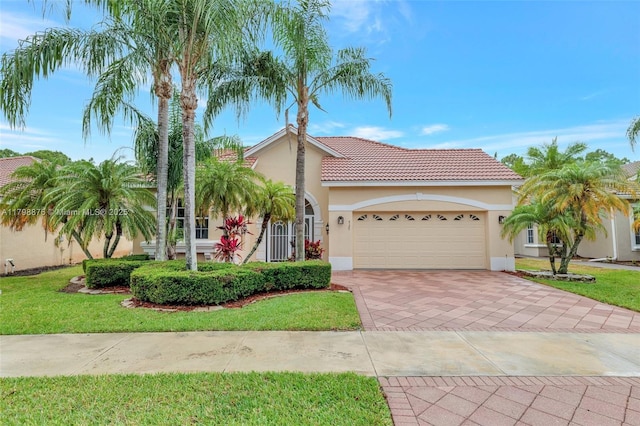 mediterranean / spanish home featuring a garage, decorative driveway, stucco siding, and a tile roof