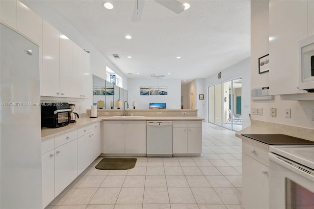 kitchen with white appliances, a ceiling fan, a sink, a peninsula, and light countertops