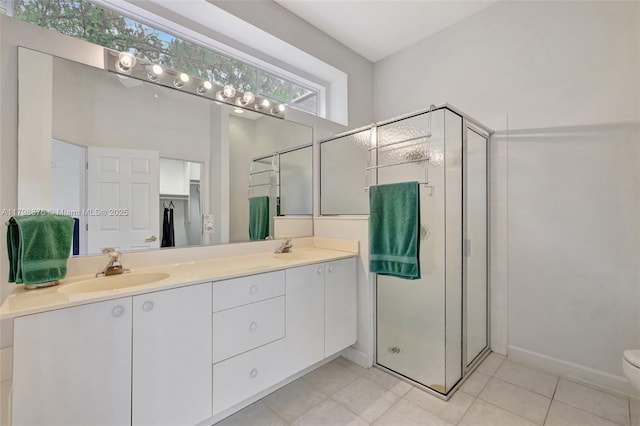 bathroom with a stall shower, tile patterned flooring, double vanity, toilet, and baseboards