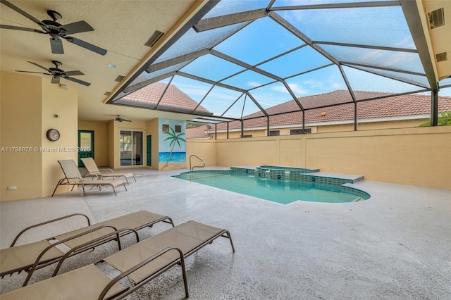 view of pool with a ceiling fan, a patio, a pool with connected hot tub, and glass enclosure