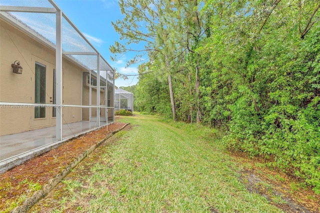 view of grassy yard with a lanai and a patio area