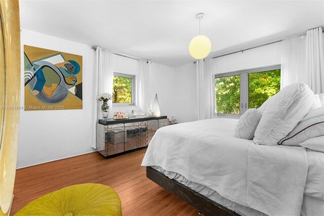 650 NE 60th St, Miami, FL 33137 - bedroom with wood finished floors, multiple windows, and baseboards