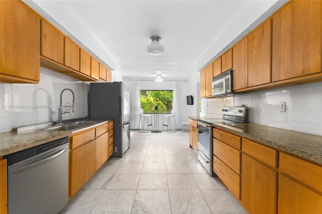 650 NE 60th St, Miami, FL 33137 - kitchen featuring stainless steel appliances, a sink, brown cabinetry, and light tile patterned floors