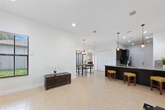 2691 NW 83rd Ter, Cooper City, FL 33024 - kitchen with a breakfast bar, a chandelier, light stone counters, hanging light fixtures, and recessed lighting