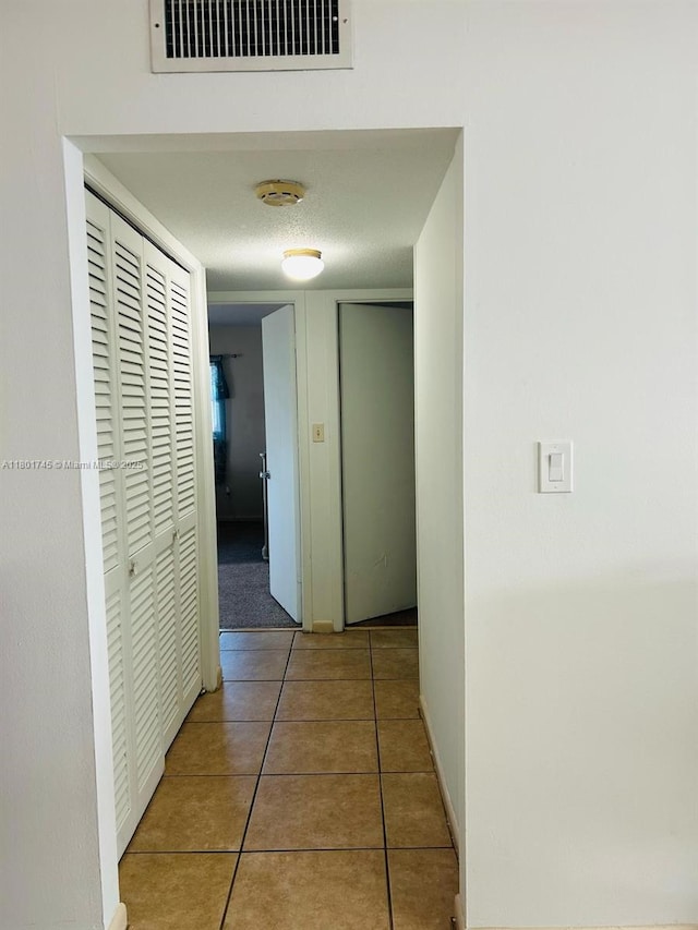 hallway featuring tile patterned floors and baseboards