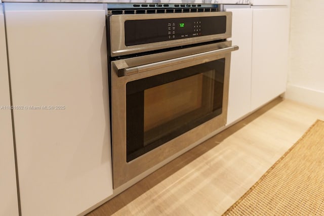 kitchen view of stainless steel oven and white cabinetry