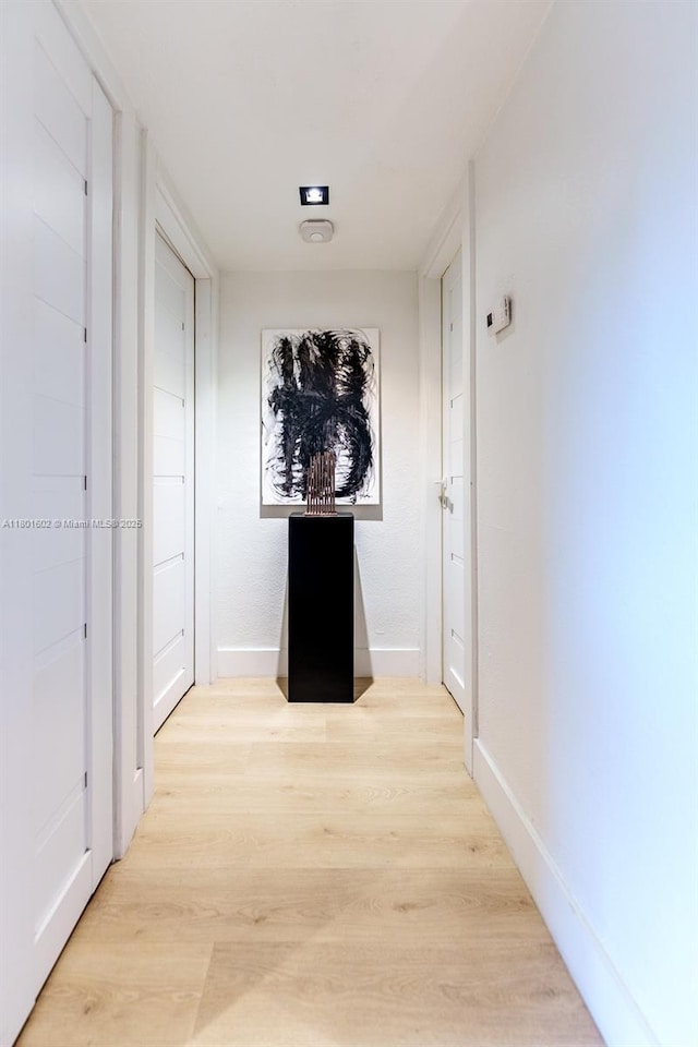 hallway featuring light wood-style flooring and baseboards