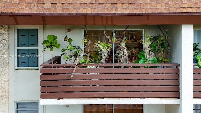 property entrance featuring a shingled roof and stucco siding