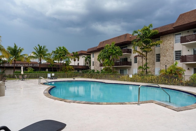 community pool with fence and a patio