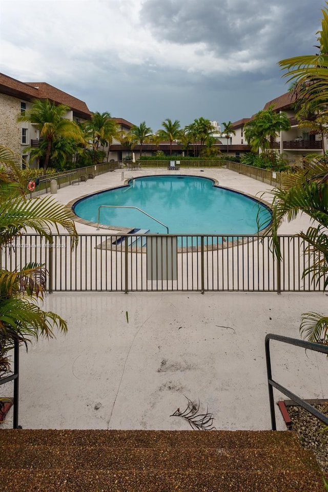 community pool featuring fence and a patio