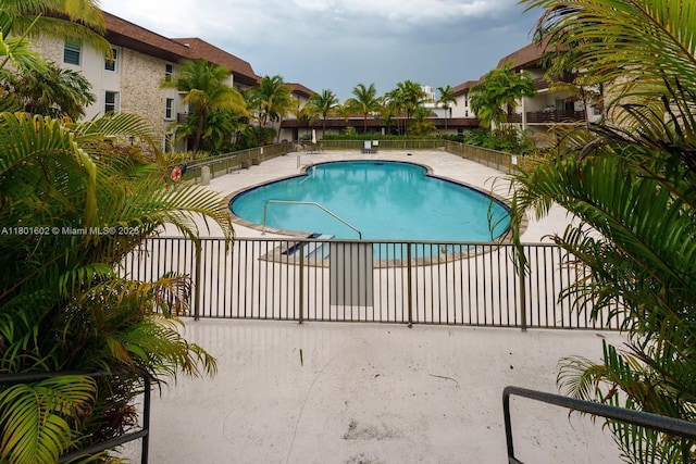 community pool with fence and a patio