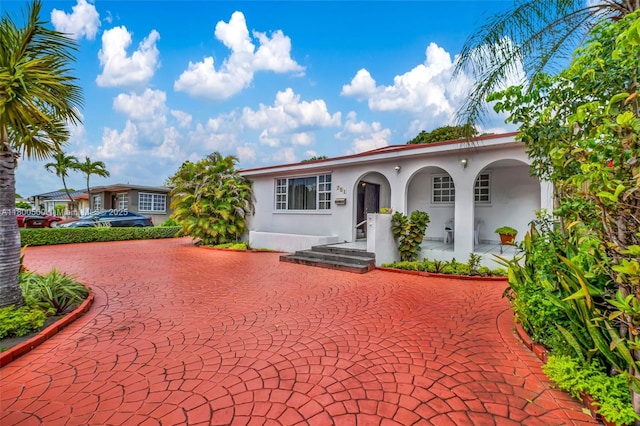 view of front of property with stucco siding, curved driveway, and covered porch
