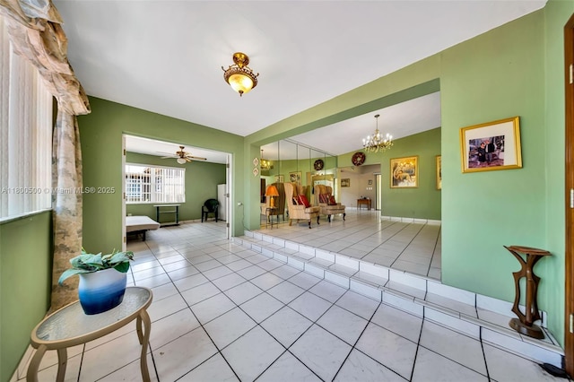 tiled living room with ceiling fan and a chandelier