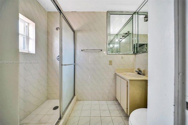 bathroom featuring a stall shower, vanity, tile walls, toilet, and tile patterned floors