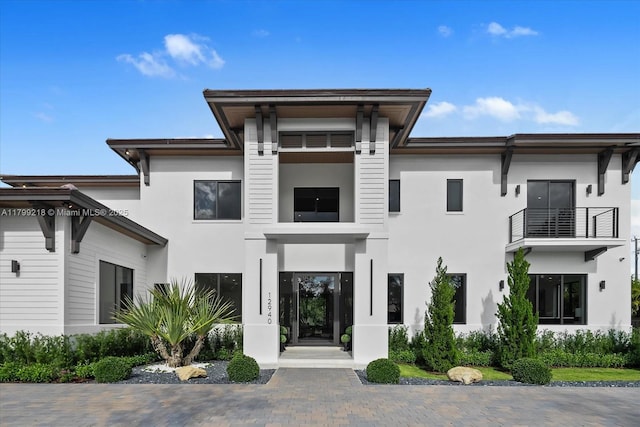 view of front of home with stucco siding and a balcony