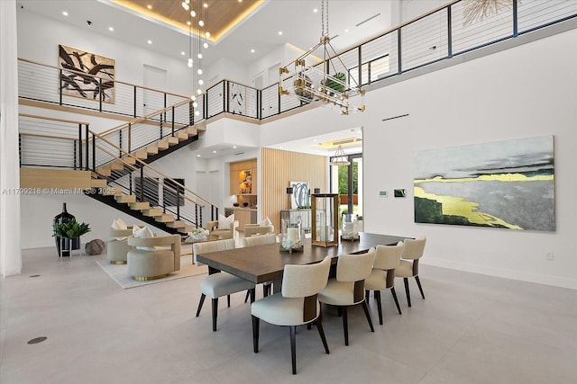 dining area with a towering ceiling, stairs, and a chandelier