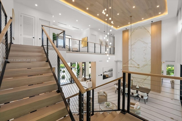 staircase with recessed lighting, a towering ceiling, a tray ceiling, and a chandelier