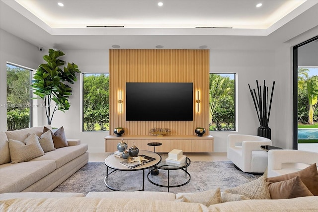 living area with a raised ceiling, recessed lighting, and healthy amount of natural light