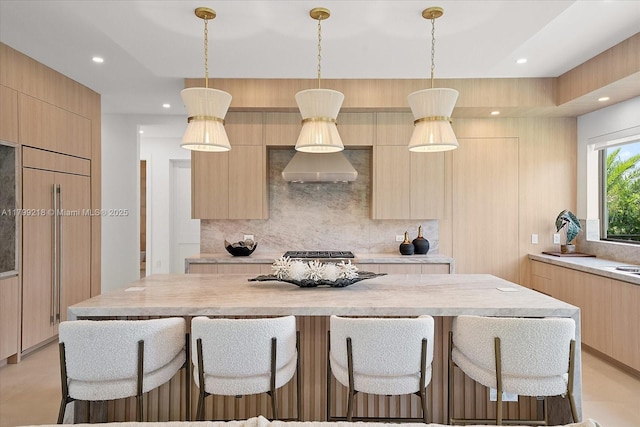 kitchen featuring modern cabinets, light brown cabinets, tasteful backsplash, a breakfast bar, and recessed lighting