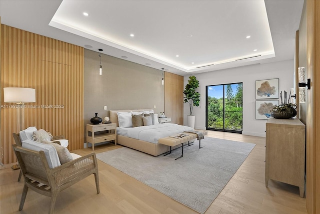 bedroom featuring a raised ceiling, light wood-style floors, and recessed lighting