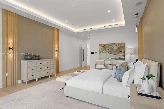 bedroom featuring recessed lighting, light wood finished floors, and a tray ceiling