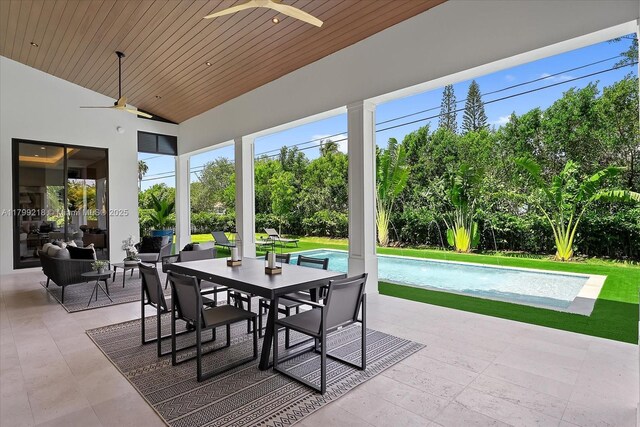 view of patio featuring ceiling fan, outdoor dining area, an outdoor pool, and view of wooded area