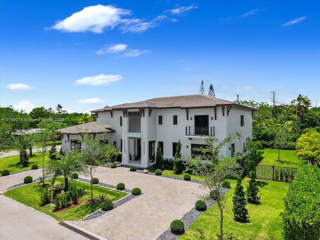 view of front of home featuring a balcony, decorative driveway, and stucco siding