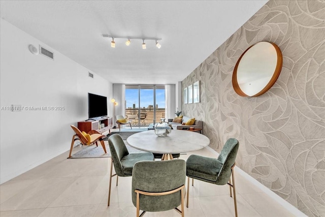 tiled dining space featuring wallpapered walls, an accent wall, and baseboards