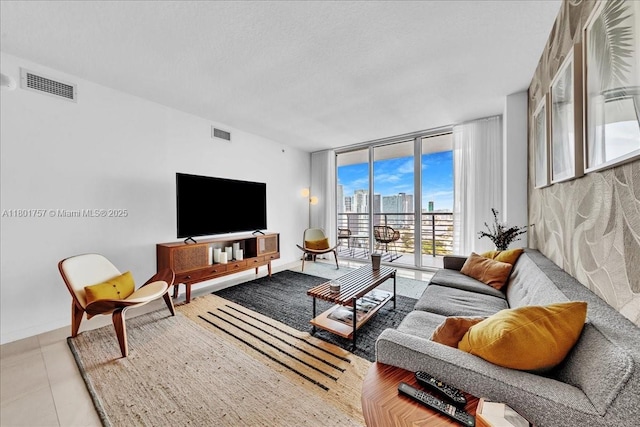 living area featuring floor to ceiling windows, light tile patterned floors, baseboards, and a textured ceiling