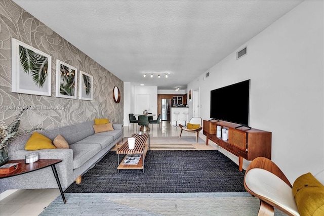 living room featuring wallpapered walls and a textured ceiling