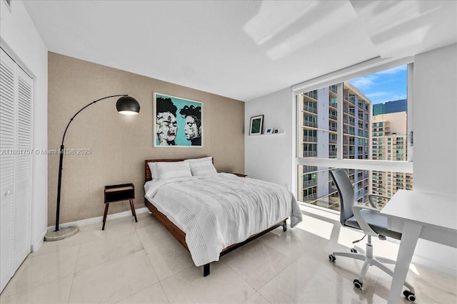 bedroom with floor to ceiling windows, a desk, and a closet
