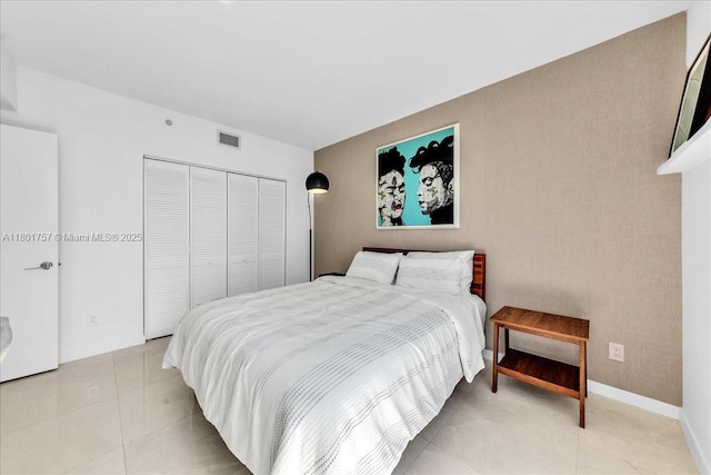 bedroom featuring a closet, light tile patterned floors, and baseboards