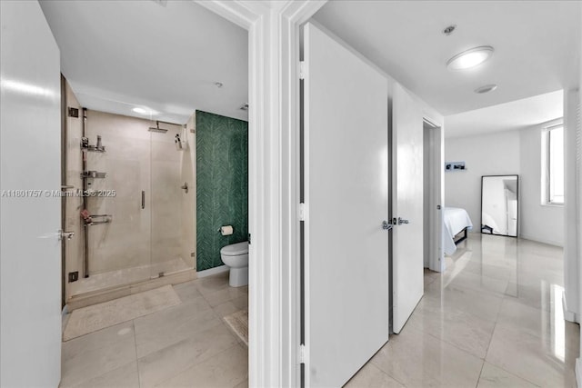 ensuite bathroom featuring a stall shower and toilet