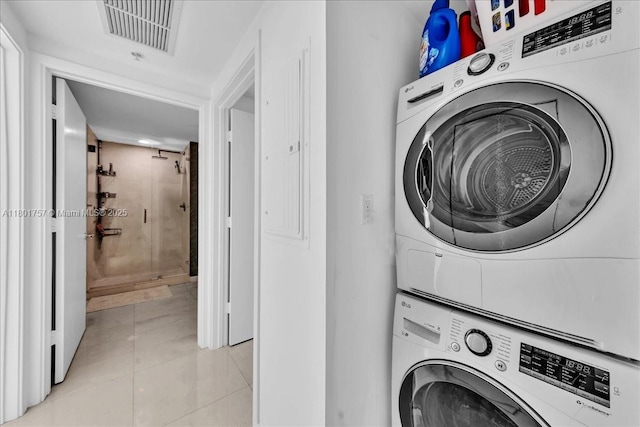 laundry area with stacked washer and clothes dryer and light tile patterned floors