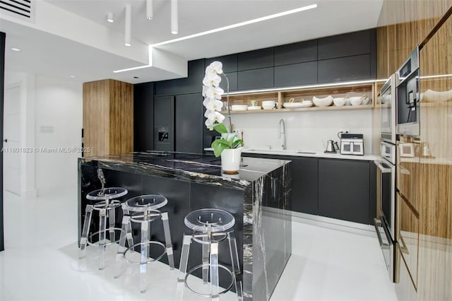 1187 NE 182nd St, North Miami Beach, FL 33162 - kitchen with modern cabinets, a sink, a breakfast bar area, and dark cabinetry