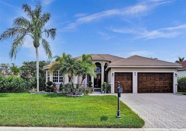 4985 NW 120th Ave, Coral Springs, FL 33076 - mediterranean / spanish-style home with a garage, decorative driveway, a front lawn, stucco siding, and a tile roof