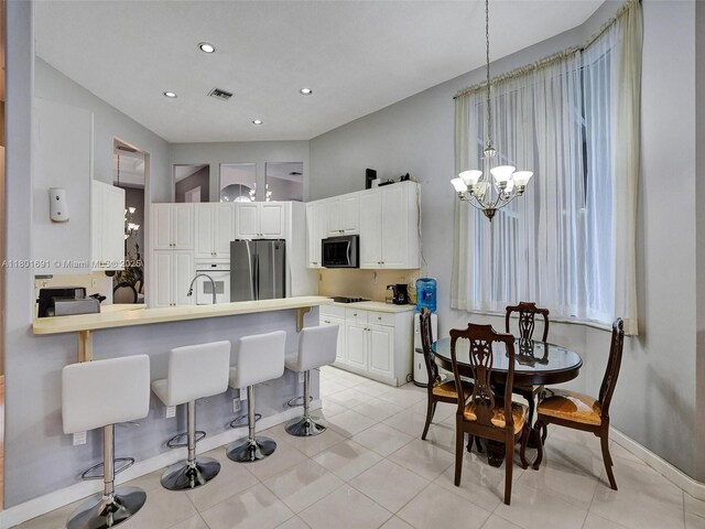 4985 NW 120th Ave, Coral Springs, FL 33076 - kitchen with appliances with stainless steel finishes, a kitchen bar, a chandelier, white cabinetry, and baseboards