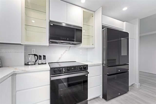 137 Golden Isles Dr Unit 305, Hallandale Beach, FL 33009 - kitchen featuring black fridge, electric stove, stainless steel microwave, white cabinets, and light stone counters