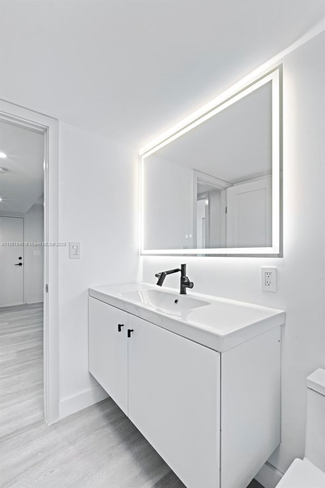 137 Golden Isles Dr Unit 305, Hallandale Beach, FL 33009 - bathroom with wood finished floors, vanity, toilet, and baseboards