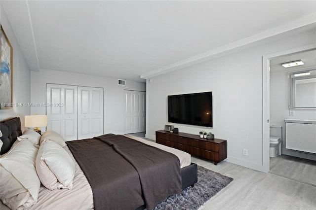 137 Golden Isles Dr Unit 305, Hallandale Beach, FL 33009 - bedroom with light wood-style floors, multiple closets, connected bathroom, and baseboards