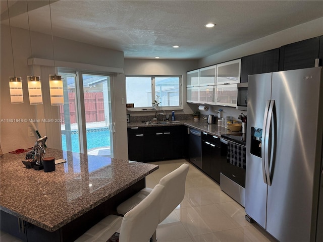 1751 SW 87th Ter, Miramar, FL 33025 - kitchen featuring appliances with stainless steel finishes, dark cabinetry, dark stone counters, a sink, and a textured ceiling