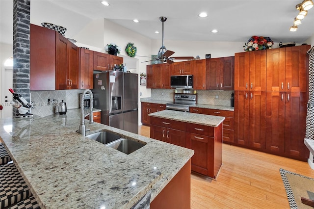 kitchen with stainless steel appliances, vaulted ceiling, a sink, a ceiling fan, and a peninsula